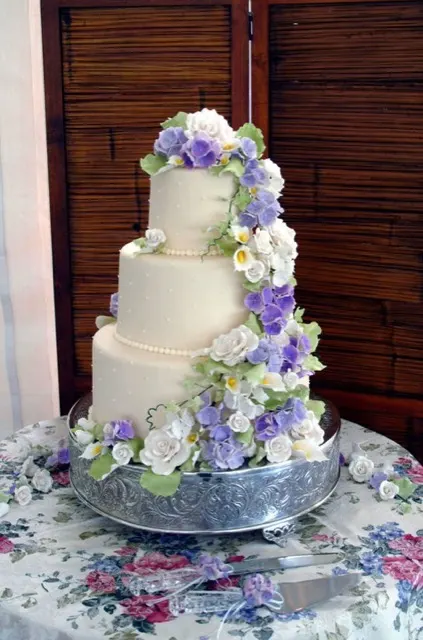 Tiered wedding cake with handmade sugar-paste flowers cascading down the side