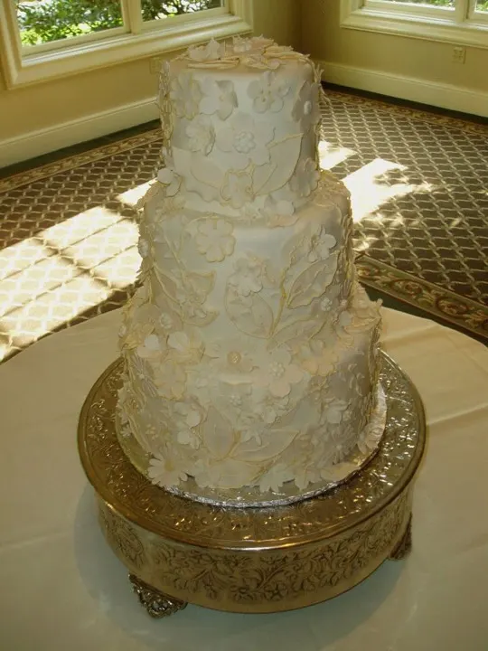 Textured white tiered wedding cake on a gold stand