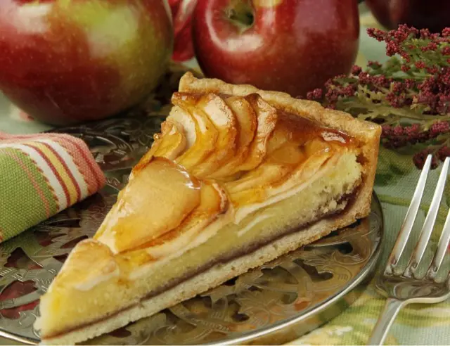 Slice of apple almond tart with fresh apples