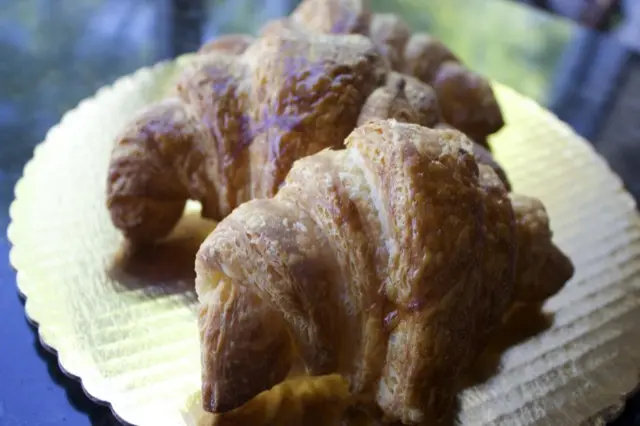 Two golden croissants on a gold board